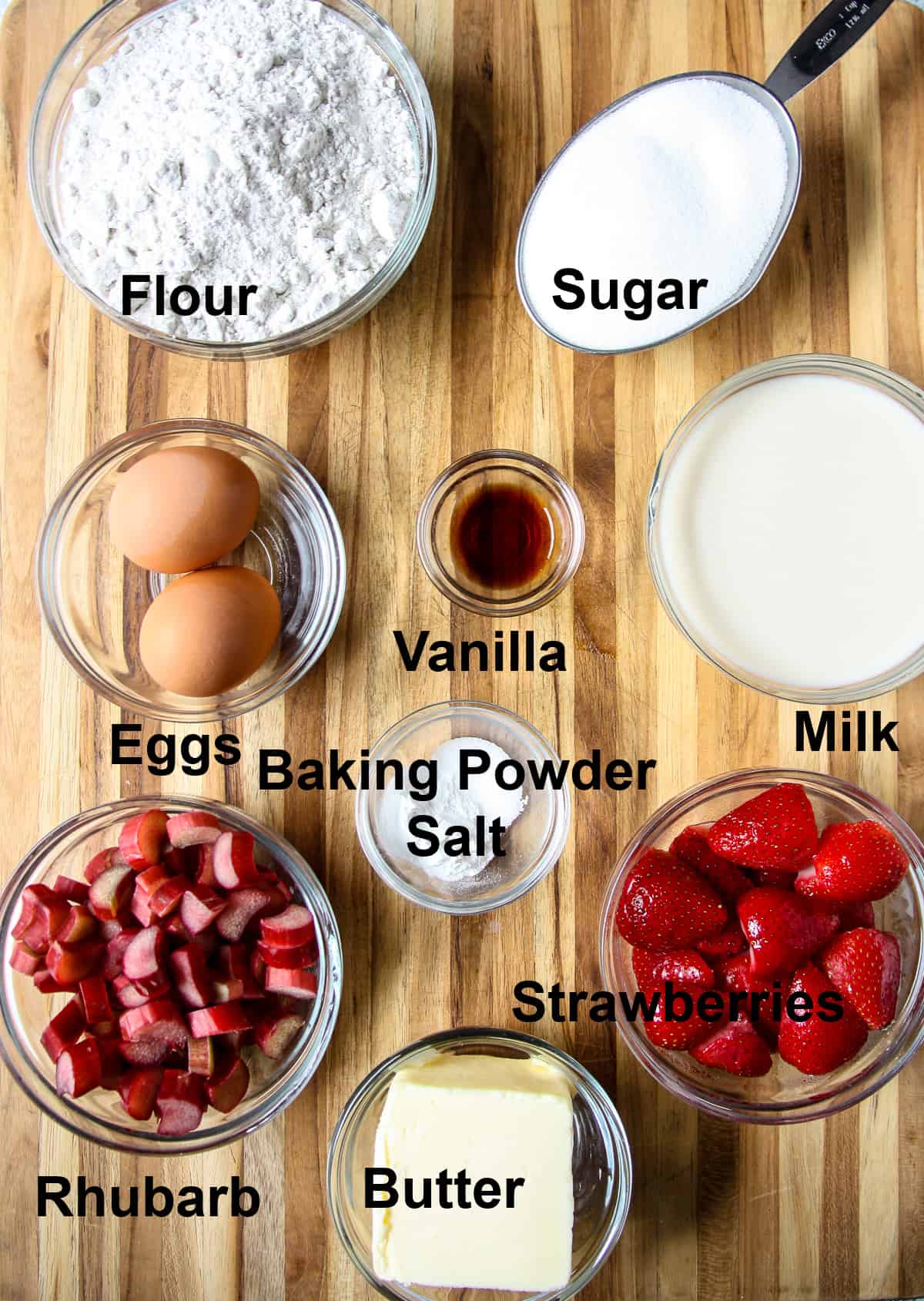 All of the ingredients need for the recipe in glass bowls on a wooden board.