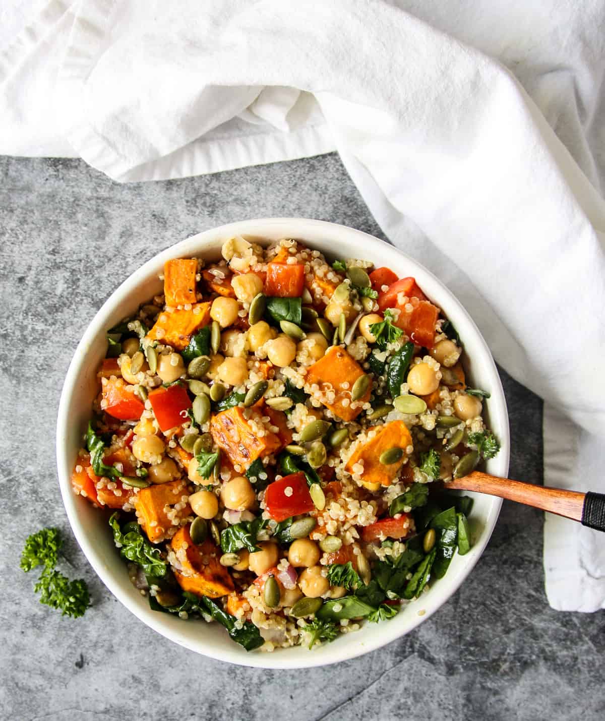 A bowl of sweet potato quinoa salad with a wooden fork.