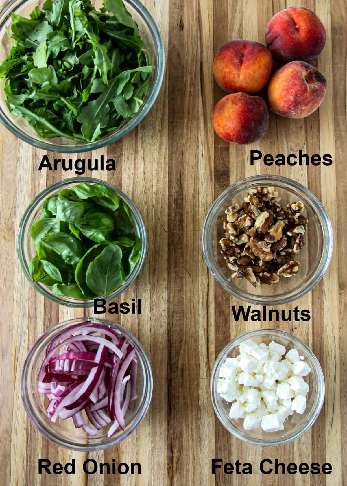 Salad ingredients in a glass bowl on a wooden board.