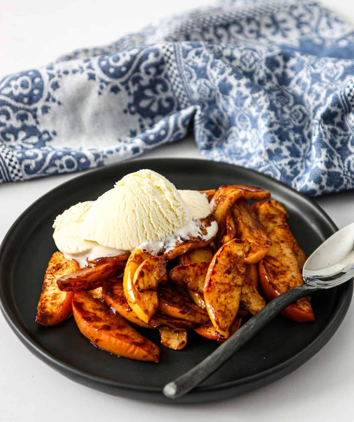 Black plate and spoon with scoops of apple and vanilla ice cream in air fryer.