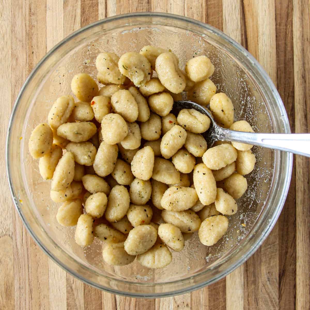 Combine raw gnocchi and seasonings in a mixing bowl.