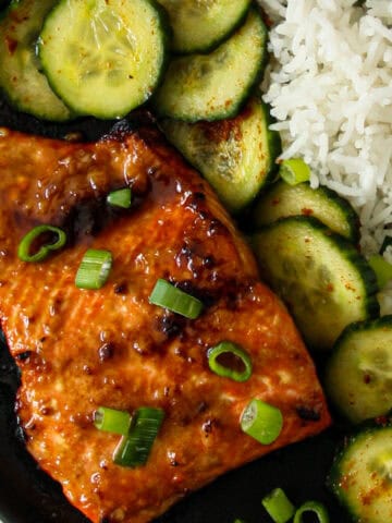 A fillet of miso butter salmon on a black plate.