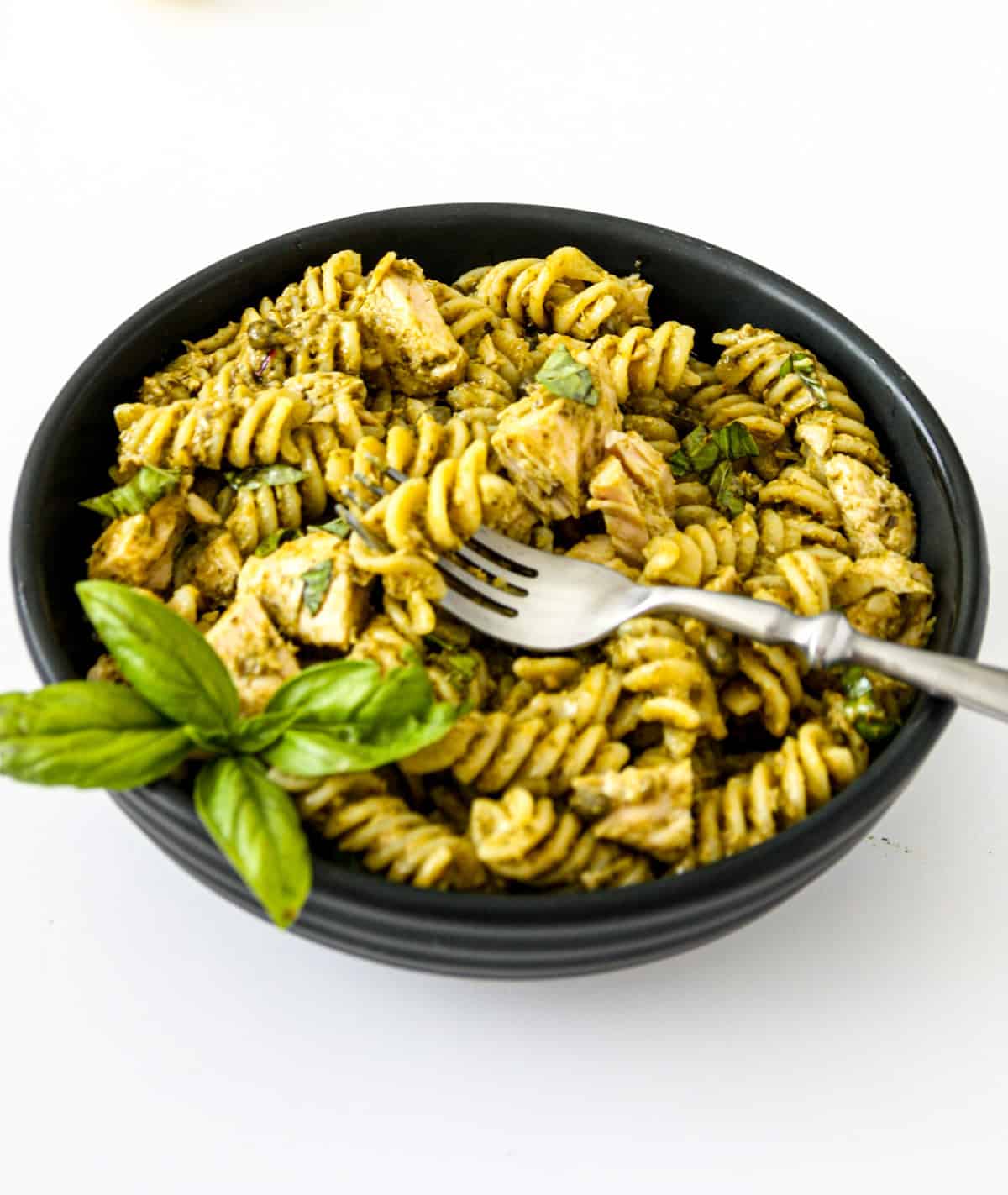 Tuna pesto pasta in a black bowl with a silver fork.
